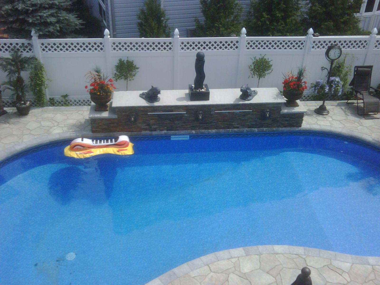 A long stone-faced feature wall frames the water and patio.