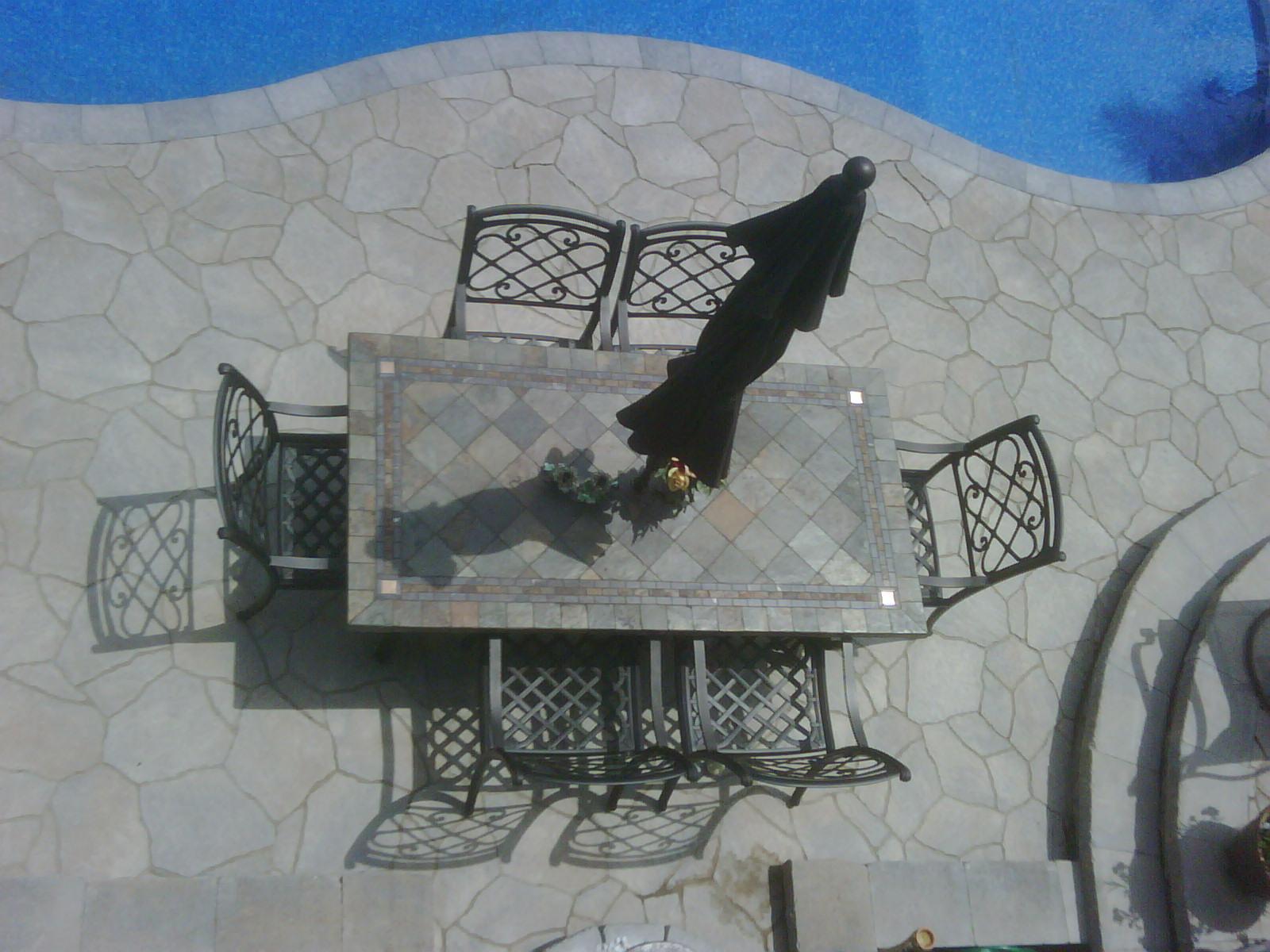 A poolside dining area with a continuous stone-patterned patio.
